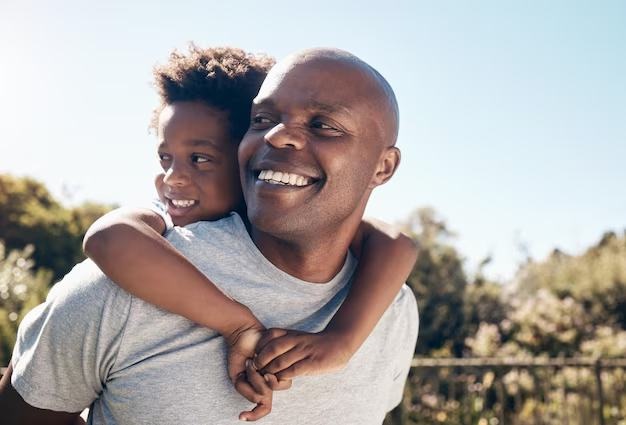 A father carrying his daughter on his back, both laughing
