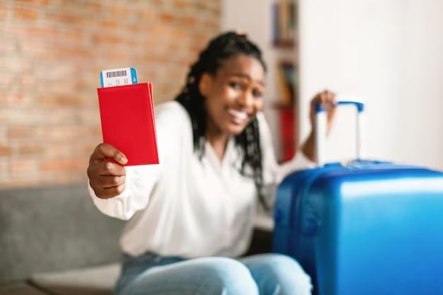 A traveller holding her passport and boarding pass beside a suitcase
